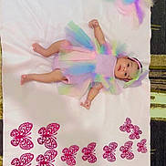 Tarasha is registered to the contest to win money with this photo: baby, infant, tutu, headband, pastel_colors, blanket, butterflies, feathers, dreamcatcher, lying_down, cute, colorful, soft_texture, decor, bracelet, indoors, carpet, pattern, child, portrait