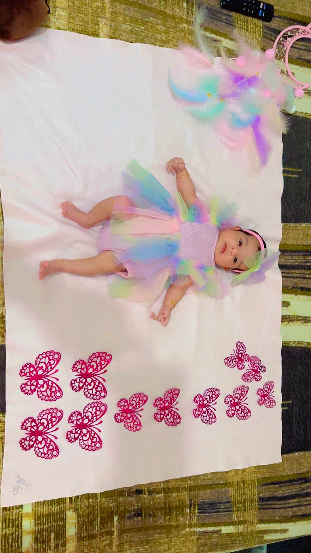 Tarasha is registered to the contest to win money with this photo: baby, infant, tutu, headband, pastel_colors, blanket, butterflies, feathers, dreamcatcher, lying_down, cute, colorful, soft_texture, decor, bracelet, indoors, carpet, pattern, child, portrait