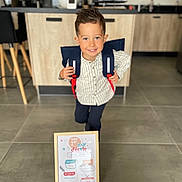 éthan participe au concours pour gagner de l'argent avec cette photo : child, boy, backpack, indoor, kitchen, floor, tile_floor, furniture, cabinet, smiling, portrait, shirt, pants, hair, sign, framed, first_day_of_school, happy, person, home