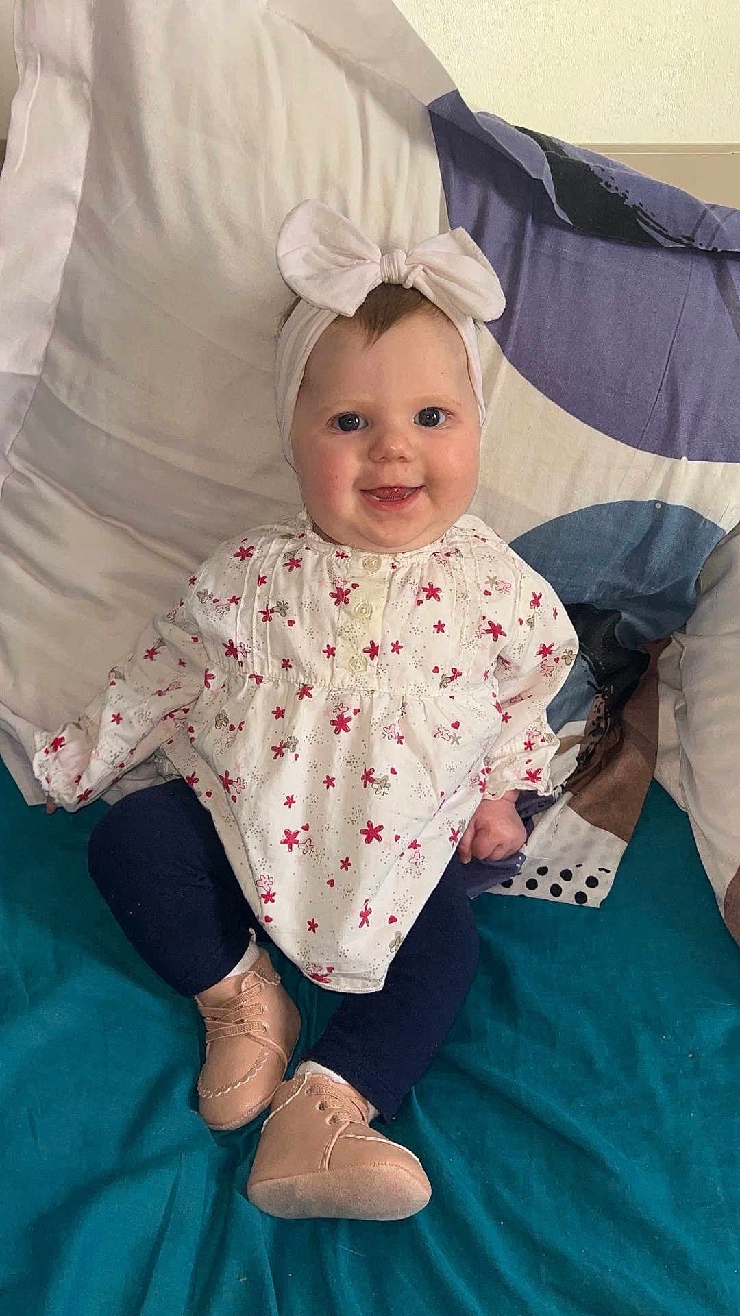 Leïya a rejoint le concours — aidez-le/la à gagner de superbes lots ! baby, child, smiling, headband, bow, flower_print, long_sleeve, leggings, shoes, bed, pillow, blanket, indoors, cute, happy, sitting, person, infant, portrait, clothing