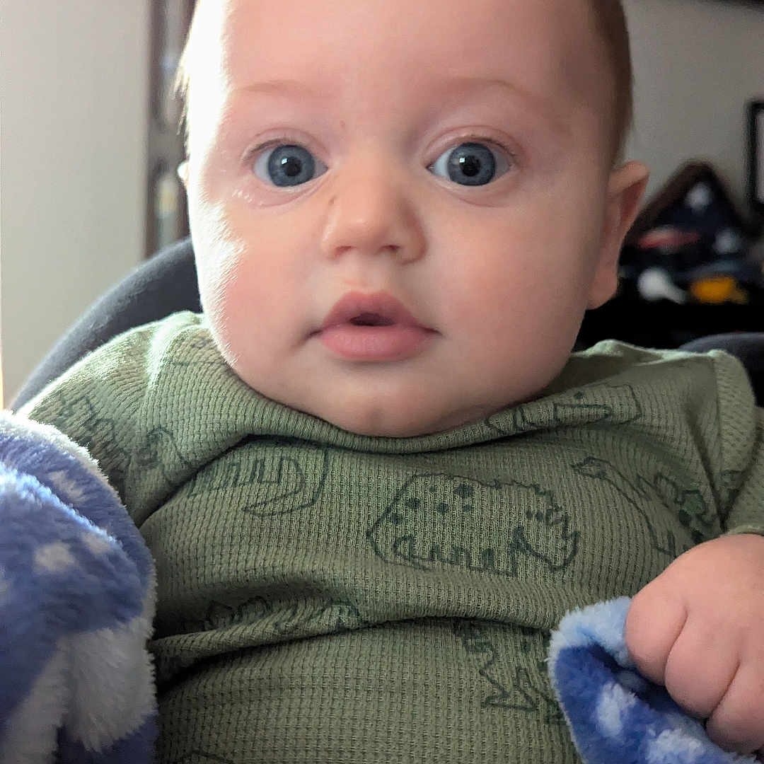 Finnick is registered to the contest to win money with this photo: baby, blanket, bodypart, clothing, couch, face, finger, furniture, hand, head, hoodie, knitwear, newborn, pants, person, photography, portrait, sweater, sweatshirt, t_shirt