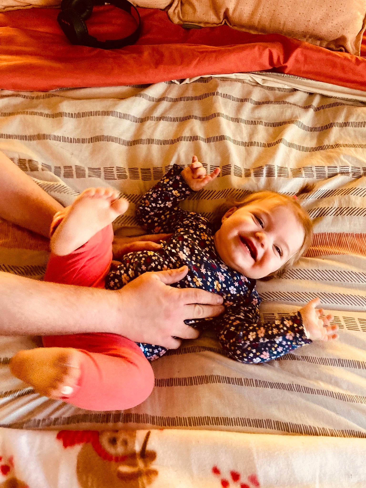 Charlie is registered to the contest to win money with this photo: baby, baby_toddler_clothing, bed, bed_sheet, bedding, bedroom, child, comfort, flooring, fun, happy, human_leg, joy, linens, orange, pattern, person, room, smile, textile