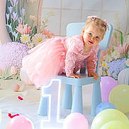 Delia a rejoint le concours — aidez-le/la à gagner de superbes lots ! toddler, child, pink_dress, blue_chair, balloons, number_one_sign, flowers, floral_backdrop, playful, indoor, portrait, birthday, cute, smiling, celebration, pastel_colors, decorations, happy, hair_bows, soft_lighting