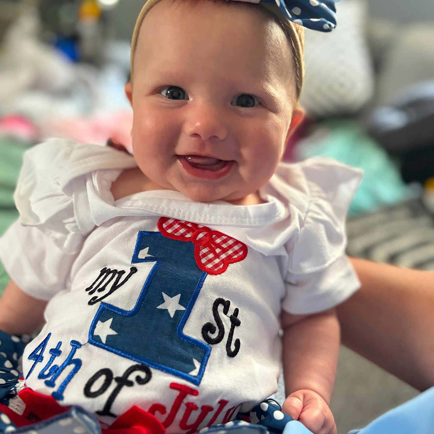 Paisleigh is registered to the contest to win money with this photo: baby, child, smiling, headband, white_clothing, red_white_blue, celebration, 4th_of_july, portrait, closeup, indoor, happy, cute, infant, festive, ribbon, polka_dot, sitting, person, holiday