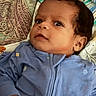 Noah is registered to the contest to win money with this photo: baby, infant, child, portrait, close_up, face, eyes, curly_hair, curious, lying_down, blue_clothing, onesie, pajamas, pillow, bed, bedding, indoor, home, soft_lighting, photography