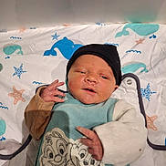 Arés participe au concours pour gagner de l'argent avec cette photo : baby, newborn, infant, face, hat, blanket, bedding, whale_pattern, starfish, sea_theme, onesie, cartoon_characters, hands, portrait, soft_lighting, cute, cozy, sleepy, crib, expression