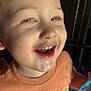 child, toddler, smile, face, orange_shirt, happy, teeth, closeup, expression, indoor, person, young_child, holding, blue_object, casual_clothing, cute, portrait, skin, eyelashes, mouth