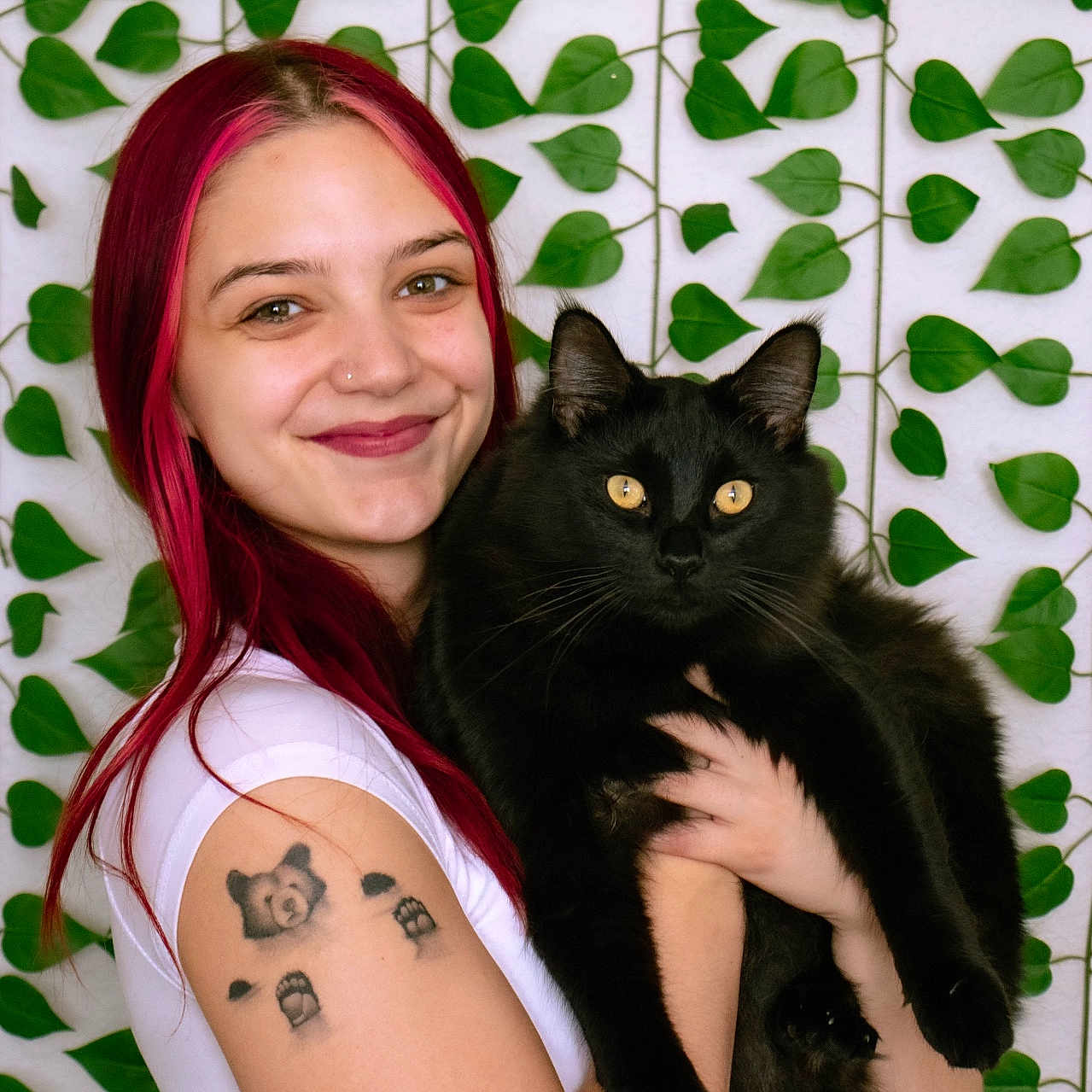 Simon joined the competition — help win amazing prizes! woman, pink_hair, black_cat, cat, tattoo, smiling, portrait, indoor, leaf_pattern, green_leaves, white_shirt, happy, pet, holding, animal, cute, face, long_hair, yellow_eyes, feline