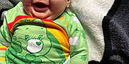 Kaylani joined the competition — help win amazing prizes! baby, child, smiling, laughing, green_clothing, plush_toy, toy, blanket, colorful, rainbow, indoor, happy, infant, cute, face, earring, soft_texture, lying_down, playful, diaper