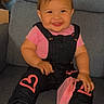 toddler, child, smiling, pink_bows, overalls, pink_shirt, hearts, black_boots, sitting, couch, indoor, happy, face, person, clothing, footwear, hair_accessory, cute, portrait, young_child