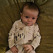 Otto joined the competition — help win amazing prizes! baby, infant, onesie, clothing, animal_print, bear, tree, couch, fabric, texture, person, child, smile, face, hand, portrait, indoor, cute, lying_down, young