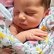 Maliah joined the competition — help win amazing prizes! baby, newborn, sleeping, swaddle, blanket, floral_pattern, hand, face, cheeks, hair, ear, towel, close_up, portrait, infant, cozy, peaceful, wrapping, soft_texture, resting