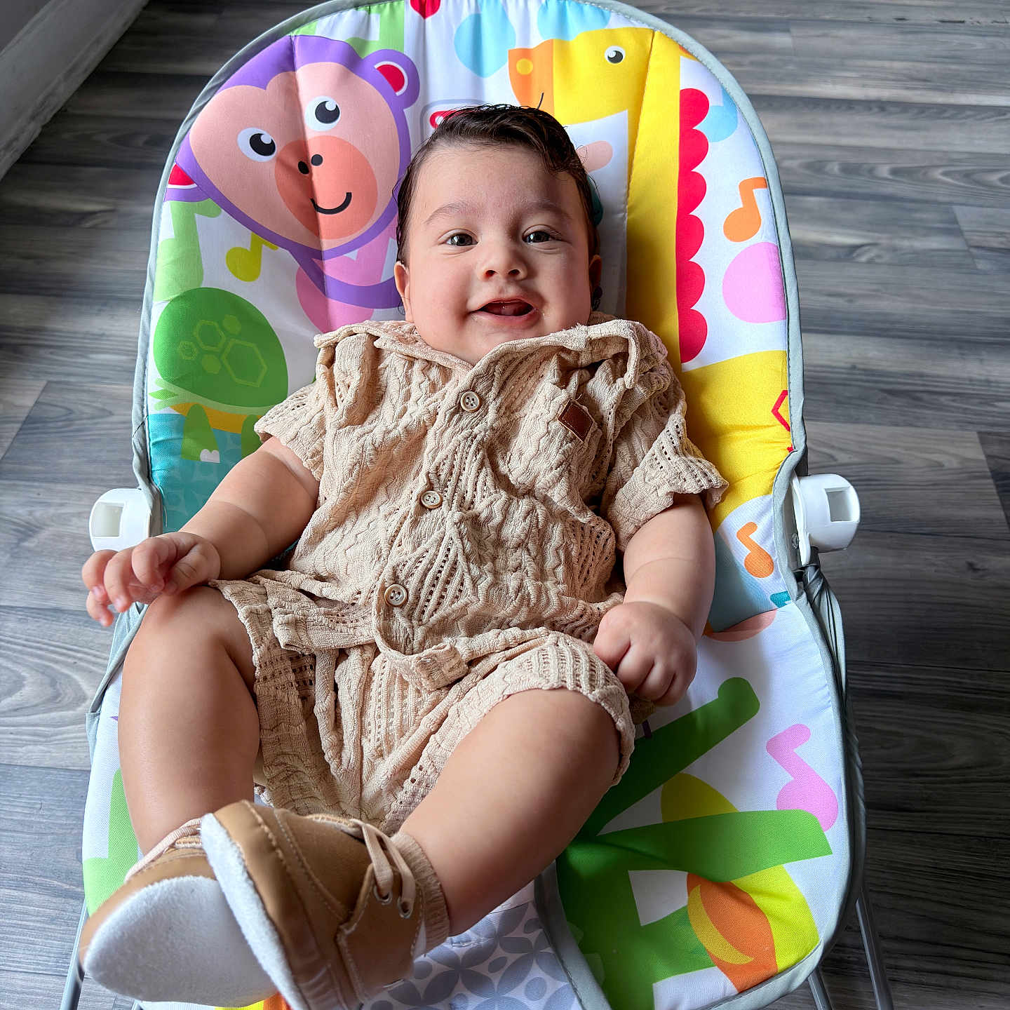 Narel joined the competition — help win amazing prizes! baby, child, infant, smiling, happy, portrait, seated, bouncer, activity_seat, knitted_outfit, beige_clothing, shoes, colorful_cushion, indoor, wood_floor, home, natural_light, face, playful, adorable