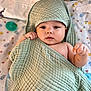 baby, towel, blanket, face, infant, child, cute, hooded_towel, lying_down, indoors, patterned_blanket, soft_texture, wrapped, hand, expression, looking_at_camera, pacifier, toy, colorful, cozy