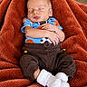 baby, sleeping, infant, portrait, blanket, cozy, indoors, sitting, clothing, socks, football, sportswear, crossed_arms, peaceful, resting, brown_blanket, blue_shirt, white_socks, closeup, child