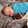 newborn, baby, sleeping, infant, portrait, face, child, blanket, plush_toy, football, blue_wrap, cozy, indoors, soft_blanket, peaceful, resting, photography, close_up, bedding, nursery