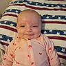 Karliah is registered to the contest to win money with this photo: baby, blue, child, cute, face, happy, hearts, indoors, infant, lying_down, onesie, pattern, pillow, portrait, red, sleepwear, smile, stars, stripes, white