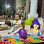 baby, balloon, birthday_party, celebration, chair, child, colorful, cup, decorations, dress, happy, indoor, letter_light, light, plant, plate, smile, table, toy, window