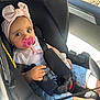 Emy a rejoint le concours — aidez-le/la à gagner de superbes lots ! baby, blue_pants, car_interior, car_seat, child, clothing, cute, cute_expression, headband, infant, pacifier, person, pink, safety_harness, seat, seatbelt, sitting, sunlight, toddler, window
