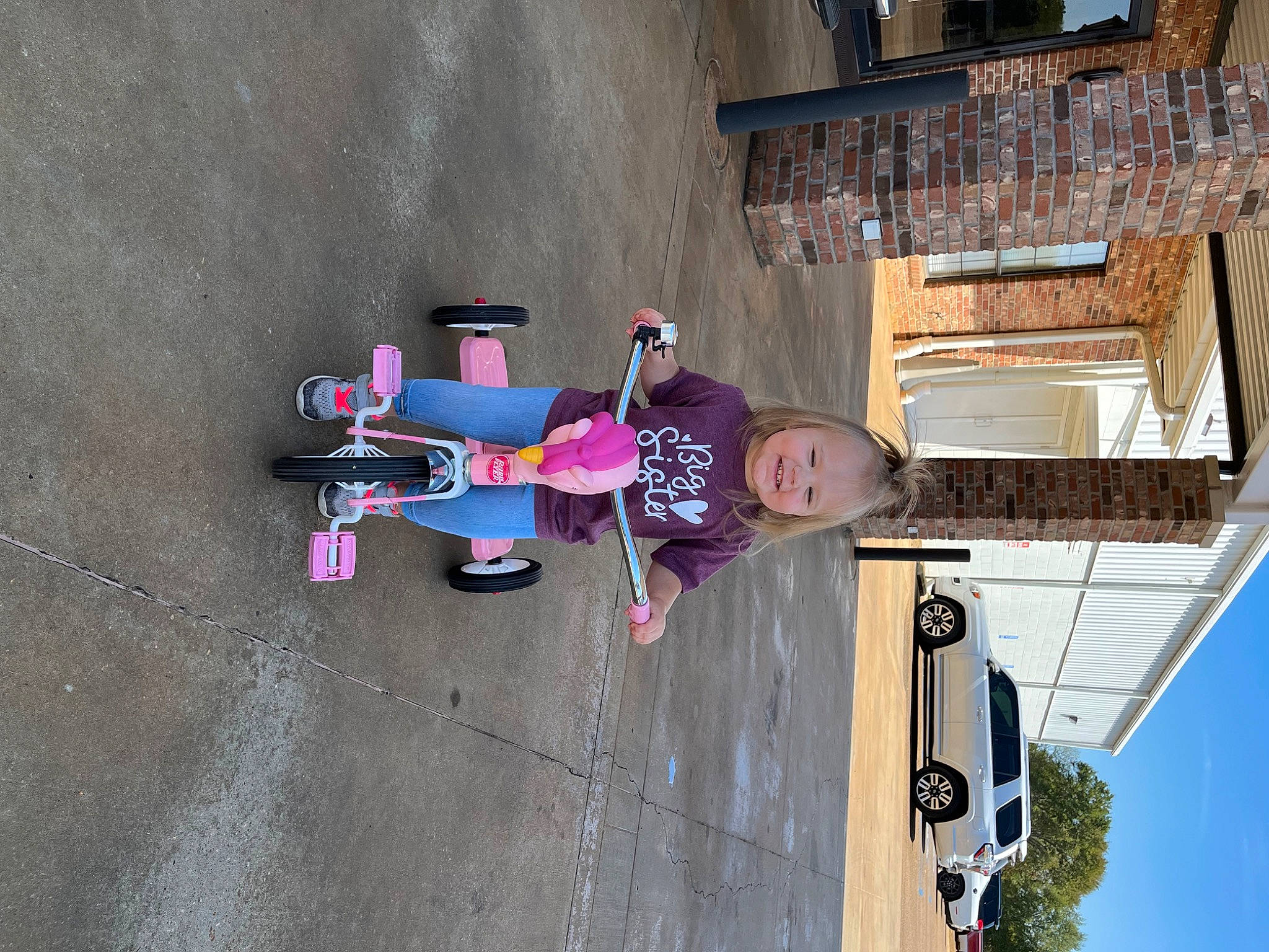 Adley is registered to the contest to win money with this photo: asphalt, bicycle_wheel, car, carmine, concrete, facade, fun, hat, joy, leisure, magenta, person, recreation, sky, smile, street, tire, toddler, travel, tree