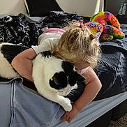 Lucy is registered to the contest to win money with this photo: child, cat, bed, blanket, hugging, indoor, animal, pet, comfort, furniture, soft, colorful, black_and_white_cat, carpet, sleepwear, curtain, cuddling, hair, rest, affection