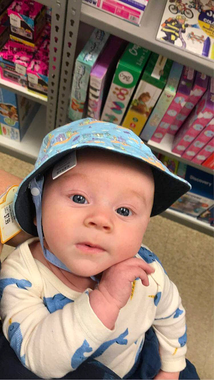 Chance is registered to the contest to win money with this photo: baby, baby_toddler_clothing, cap, cheek, child, cool, electric_blue, eye, fashion_accessory, fun, happy, headwear, helmet, person, product, retail, shelf, shelving, skin, smile