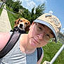 Belle is registered to the contest to win money with this photo: person, dog, beagle, backpack, hat, pin_on_hat, glasses, sidewalk, grass, sky, building, trees, pole, selfie, portrait, nose_piercing, summer, walking, suburban, happy