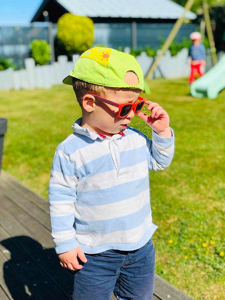 Marceau participe au concours pour gagner de l'argent avec cette photo : baby, baseball_cap, cap, eyewear, fun, goggles, grass, happy, hat, headgear, headwear, leisure, person, plant, recreation, sleeve, street_fashion, sun_hat, sunglasses, toddler