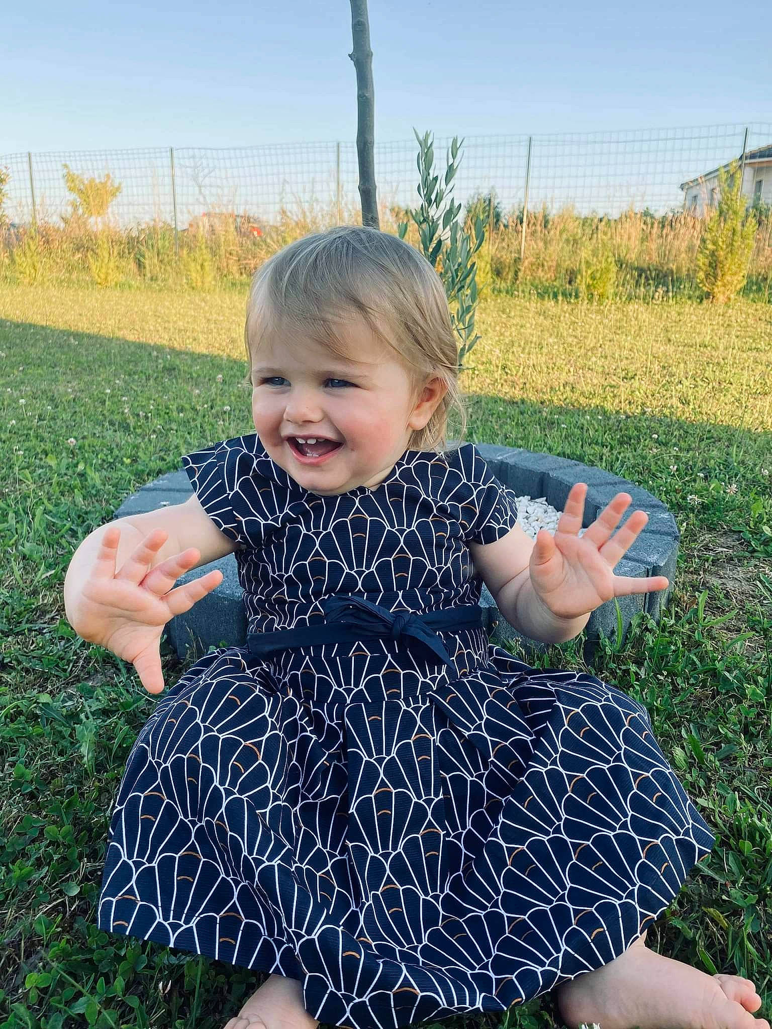 Taïs a rejoint le concours — aidez-le/la à gagner de superbes lots ! baby_toddler_clothing, day_dress, dress, finger, fun, gesture, grass, hand, happy, joy, leaf, one_piece_garment, people_in_nature, person, photograph, plant, sky, sleeve, smile, summer