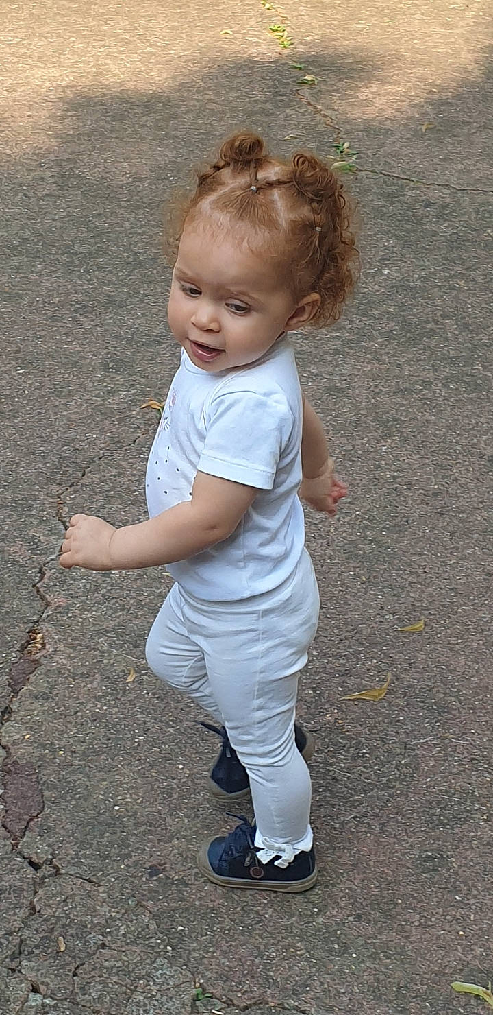 Ilyana participe au concours pour gagner de l'argent avec cette photo : asphalt, baby, baby_toddler_clothing, child, concrete, fun, gesture, grass, hairstyle, happy, human_leg, people_in_nature, person, road_surface, sidewalk, sleeve, soil, toddler, tree, waist