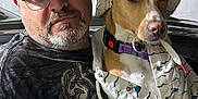 Daphne is registered to the contest to win money with this photo: man, dog, hat, glasses, clothing, portrait, indoor, casual, beard, pet, apparel, face, headwear, animal, person, seated, expression, closeup, matching, accessory