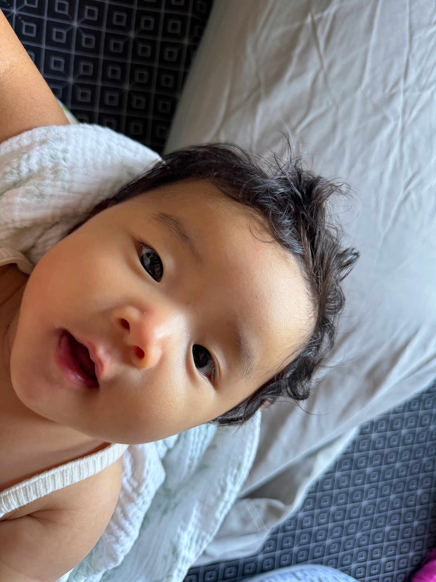 Fandana is registered to the contest to win money with this photo: baby, infant, face, eyes, hair, blanket, bed, sheet, skin, portrait, closeup, child, curious, expression, indoor, soft, white, texture, person, young