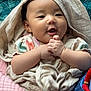 baby, child, infant, cloth, blanket, hand, face, smile, happy, person, fabric, wrapped, cute, skin, head, sitting, indoors, colorful, accessory, soft