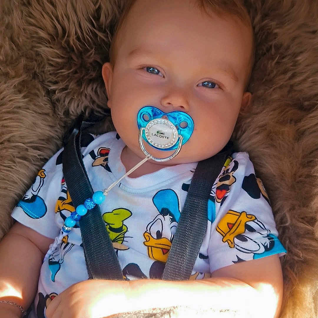 Këssïm participe au concours pour gagner de l'argent avec cette photo : accessory, baby, bead_clip, blanket, blue_pacifier, car_seat, cheeks, close_up, clothing, cute, donald_duck_print, fur_lining, hands, infant, onesie, pacifier, portrait, seat_strap, smiling, sunlight