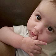 Lance is registered to the contest to win money with this photo: baby, child, face, hand, fingers, eyes, curious, portrait, infant, skin, expression, closeup, person, cute, young, sitting, indoors, white_clothing, soft_light, candid