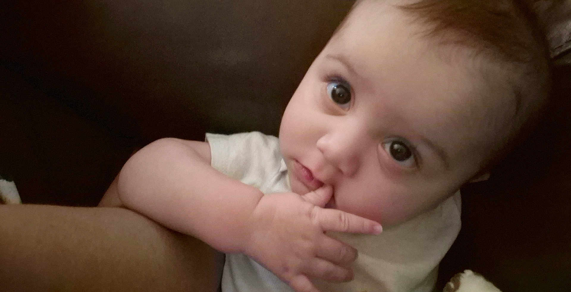 Lance is registered to the contest to win money with this photo: baby, child, face, hand, fingers, eyes, curious, portrait, infant, skin, expression, closeup, person, cute, young, sitting, indoors, white_clothing, soft_light, candid