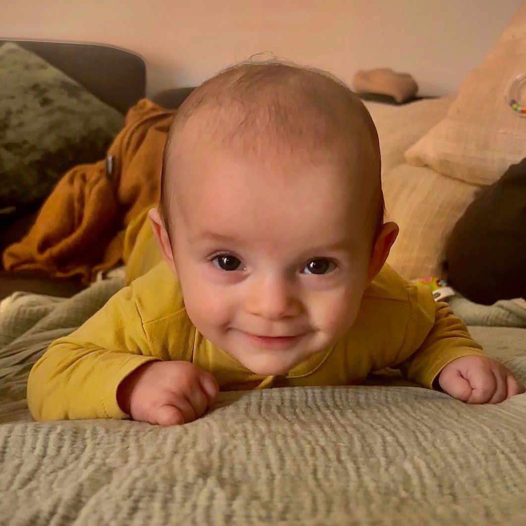 Ary a rejoint le concours — aidez-le/la à gagner de superbes lots ! baby, bed, blanket, child, cozy, cushion, cute, eyes, face, happy, head, homedecor, indoor, infant, portrait, small_hands, smile, soft_lighting, tummy_time, yellow_clothing