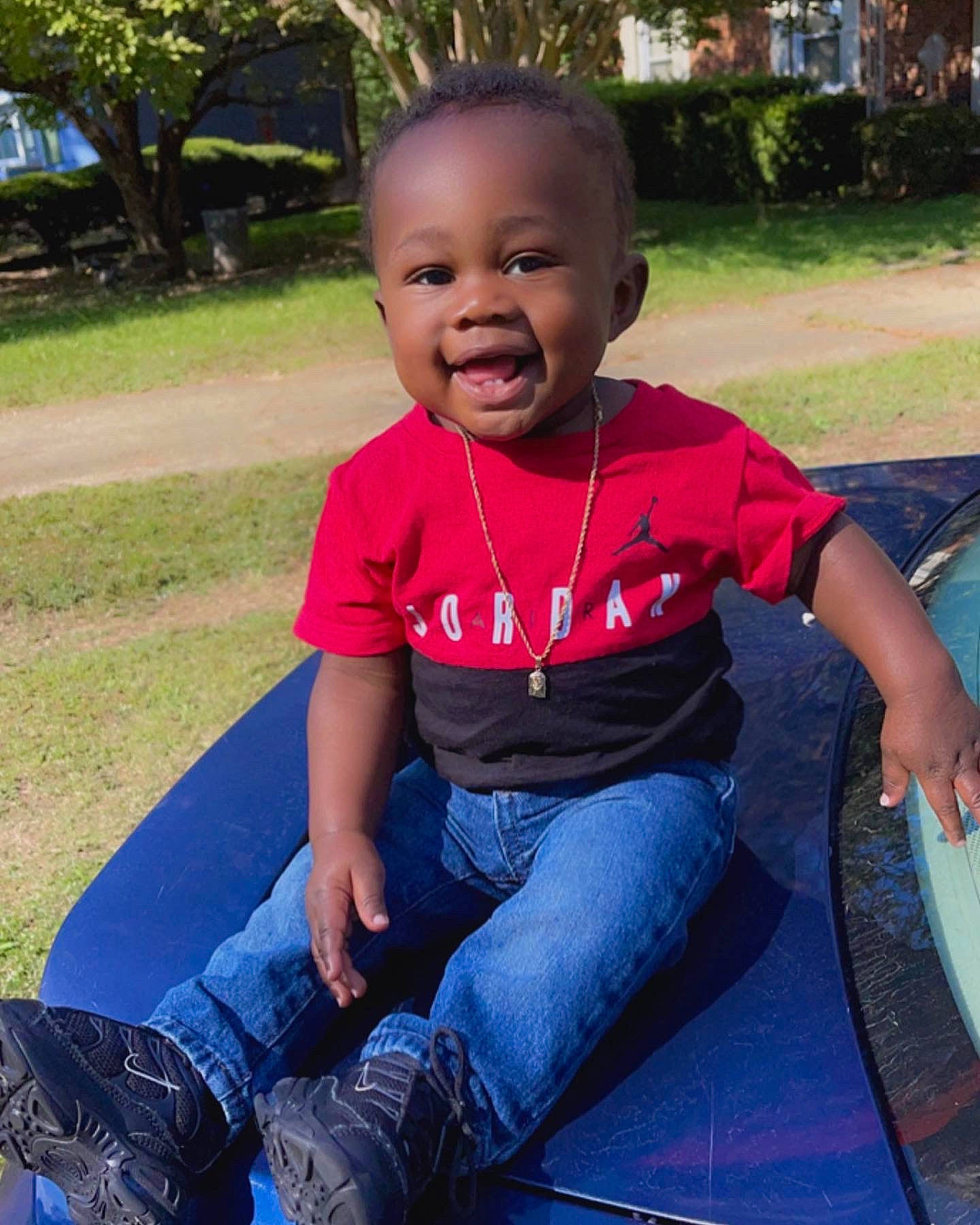 Zyan is registered to the contest to win money with this photo: baby_toddler_clothing, clothing, cool, eye, facial_expression, grass, hairstyle, happy, head, jeans, leaf, leg, leisure, person, plant, public_space, smile, sneakers, t_shirt, toddler