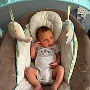 Grayson is registered to the contest to win money with this photo: baby, infant, onesie, baby_bouncer, plush_toys, cushion, face, hand, foot, striped_clothing, indoor, wall, power_outlet, curious_expression, soft_toys, baby_girl_or_boy, head_support, fabric, newborn, resting