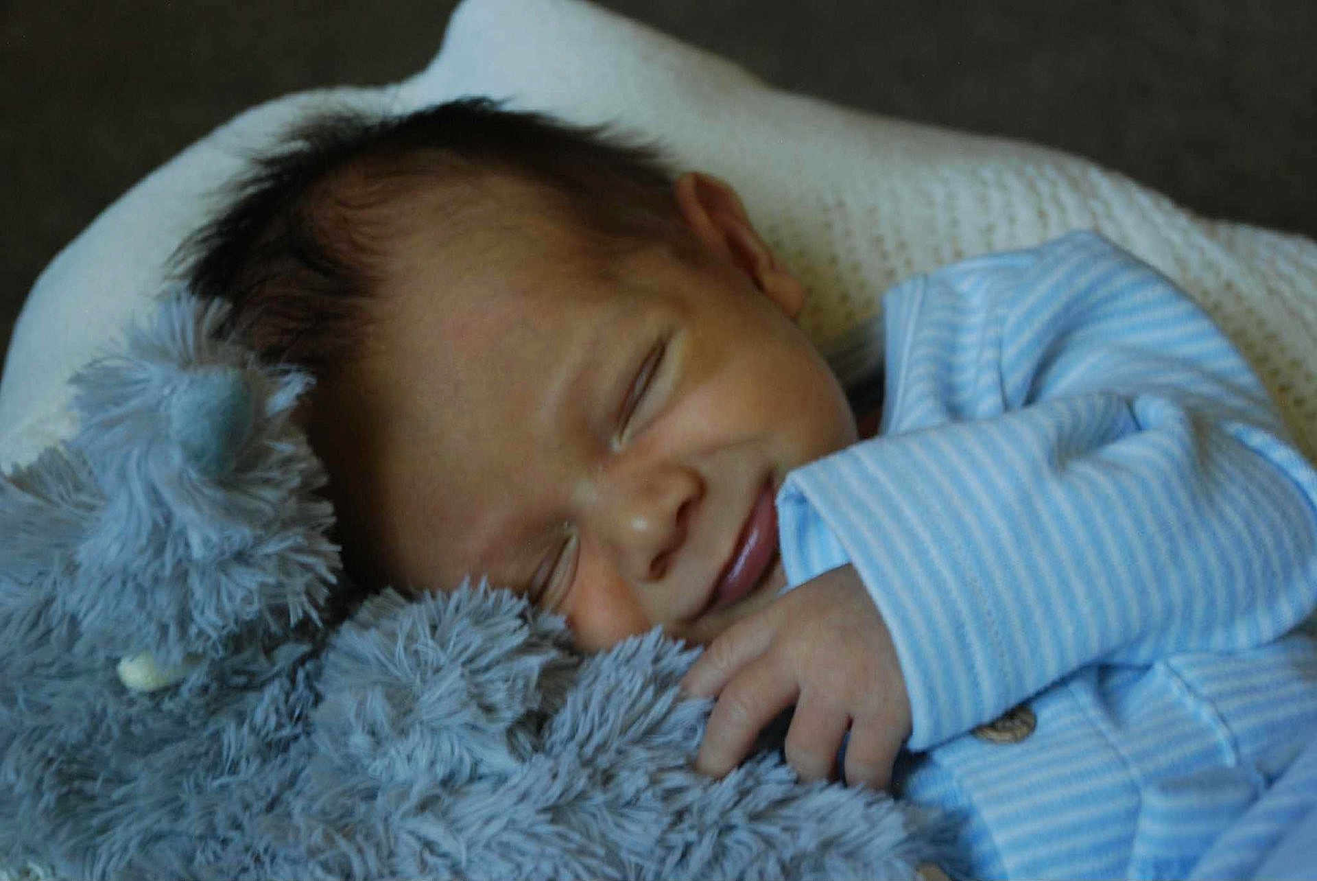 Grayson joined the competition — help win amazing prizes! baby, sleeping, teddy_bear, plush_toy, blue_onesie, infant, smile, hand, face, closed_eyes, soft_texture, cuddling, comfort, cute, child, resting, cozy, indoor, portrait, peaceful