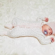Shaxrizoda is registered to the contest to win money with this photo: baby, infant, child, lying_down, sleeping, pacifier, pink_bow, white_clothing, onesie, frills, floral_bedding, bed, portrait, indoor, closeup, baby_fashion, cute, stretching, photography, watermark
