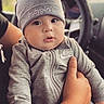 adult, baby, beanie, car, car_seat, child, close_up, face, fashion, gray_clothing, hand, indoor, infant, looking_at_camera, portrait, safe, sitting, tracksuit, vehicle, wide_eyes