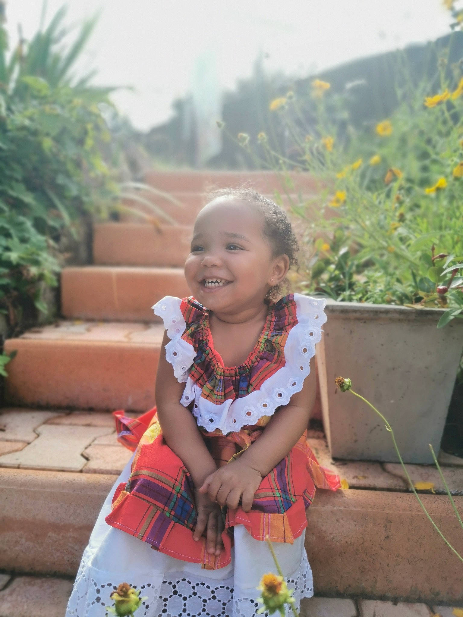 Elyne participe au concours pour gagner de l'argent avec cette photo : day_dress, dress, eye, face, flower, flowerpot, grass, happy, head, joy, leisure, morning, neck, people_in_nature, person, plant, skin, smile, temple, toddler