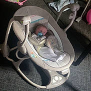 Luca is registered to the contest to win money with this photo: baby, pacifier, baby_rocker, blanket, toy, carpet, door, books, storage_box, indoor, sleeping, child, person, floor, furniture, clothing, soft_toy, baby_bedding, infant, quiet