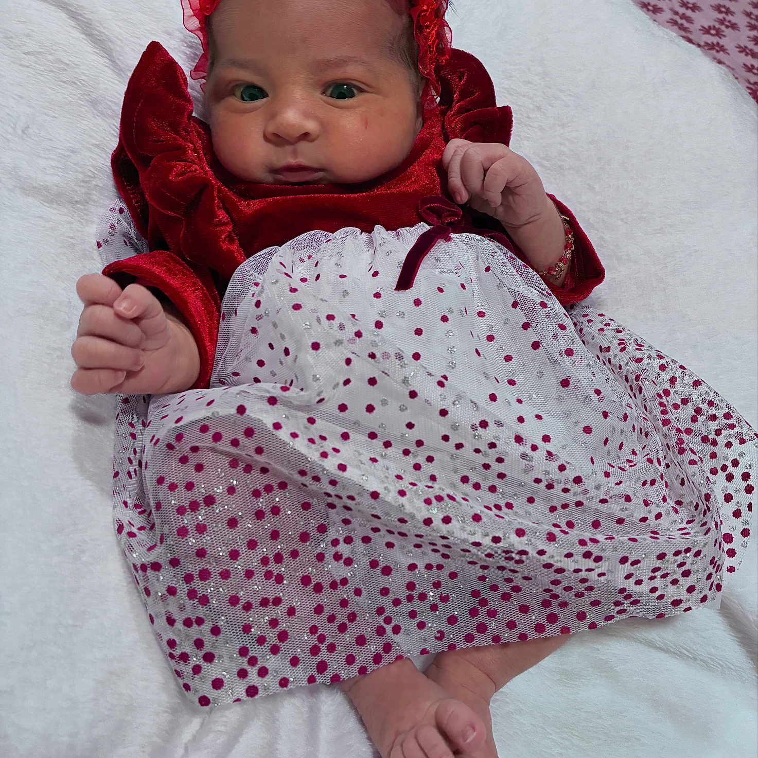 Ashley is registered to the contest to win money with this photo: baby, infant, dress, red, white, polka_dot, headband, blanket, feet, hands, face, portrait, cute, newborn, sleepwear, lying_down, indoor, soft_texture, fabric, child