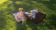 Emerlynn is registered to the contest to win money with this photo: child, toddler, baby, outdoor, grass, sunlight, portrait, crawling, curious, smiling, yellow_bow, dress, teddy_bear, stuffed_animal, suitcase, vintage, picnic, nature, playful, photography