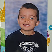 Charly participe au concours pour gagner de l'argent avec cette photo : child, boy, smiling, school_portrait, hogwarts_logo, t_shirt, short_hair, teeth, blue_background, studio_photo, face, eyes, ears, portrait, kid, young_child, happy, centered, indoors, photo_print
