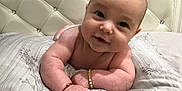 Dolly is registered to the contest to win money with this photo: arm, baby, bed, bedding, bracelet, child, closeup, cute, face, hand, happy, headboard, indoors, infant, lying_down, pattern, person, skin, sleeping_area, smiling