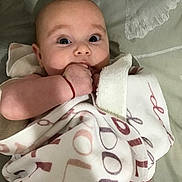 Dolly joined the competition — help win amazing prizes! baby, blanket, child, cozy, curious, cute, expression, face, hand, indoors, infant, lying_down, pattern, person, portrait, skin, sleepwear, soft_surface, wrapped, young