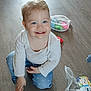 Elysianna participe au concours pour gagner de l'argent avec cette photo : child, toddler, smiling, blue_eyes, white_shirt, blue_jeans, kneeling, wooden_floor, toys, mesh_bag, indoor, happy, cute, playing, person, baby, casual_clothing, light_hair, small_teeth, cheerful